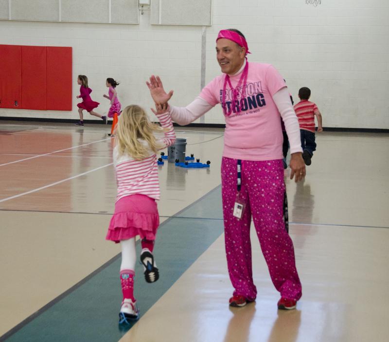 Physical education teacher Joe Resmini gives a student a high five while dressed head to toe in pink. BY GEORGIA SPARLING