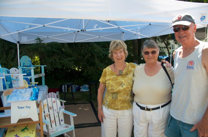 Artist Sarah Brown of Rochester stands with friends Kathy and Frank Lynch at her booth. Brown paints Adirondack chairs for kids. BY GEORGIA SPARLING