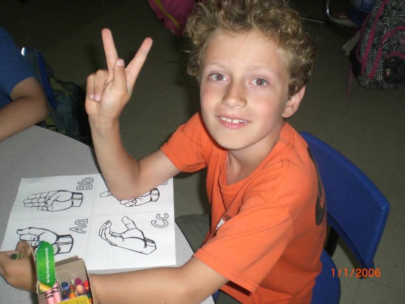 The kids enjoyed learning sign language, said Kate Oleson. They even practiced at home and asked to study it more. Above, John Bowman practices the letter "v." COURTESY KATE OLESON