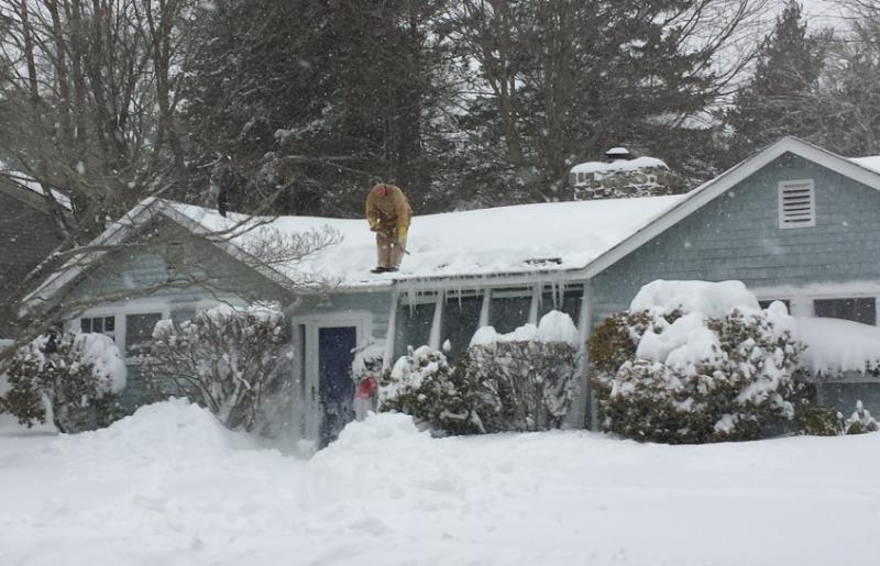 A Marion man clears snow from his roof. BY HOLLIE DANHAUSER