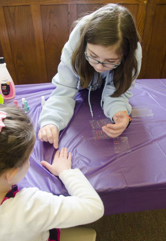 Junior Friends of the Library member Alice DeCicco-Carey bedazzles one little girl's fingernails. BY GEORGIA SPARLING