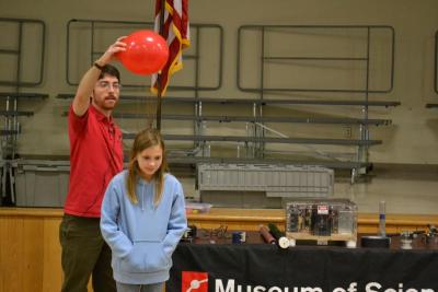 Using a balloon, Andy Hall uses negative charges to make Rebecca Milde's hand stand on end. BY JENNIFER HESHION