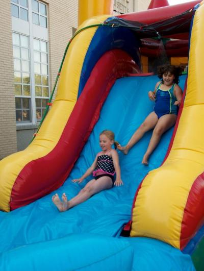 Corinne Hibbert, left, and Jamie MacKenzie slip down the slide into a pool of water. BY GEORGIA SPARLING