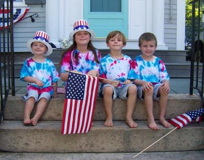 From left, Connor Callahan, 2, Julia Reilly, 9, Gustav Reilly, 5, and Ryan Callahan, 5, wait in the shade for the runners. BY MATTHEW BERNAT