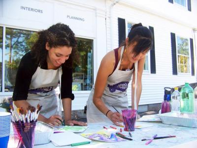 From left, Gabrielle Ferreira and Monica Chiang prepare an art activity for children. The two helped out at the New Bedford Art Museum’s artMOBILE, parked on Spring Street. BY MATTHEW BERNAT