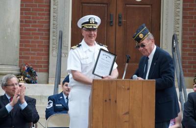 Commander Paul Brawley, the principal speaker at the ceremony, receives a plaque from American Legion Commander Michael Lamoureux. BY GEORGIA SPARLING