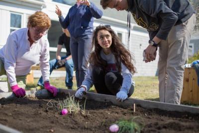 Tabor Academy Associate Director Center for International Students and Associate Director of Communications Merry Conway, left, Hope Hastings, 17, of Scotland, and Chase Cooper, 16, of Bermuda, right, place beans in a garden bed. BY CAROLYN BICK