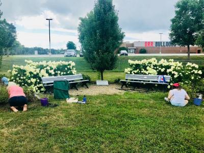 Volunteers work on the dana Dourdeville memorial garden, located near the high school's track field. BY CHRIS REAGLE