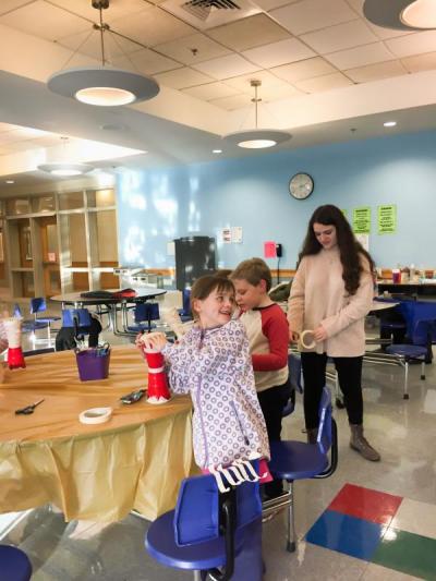 Eva Kirk and Willem Haley work on taping their drums while high school junior and volunteer Brianna Lynch provides tape. Photo by: Grace Ballenger