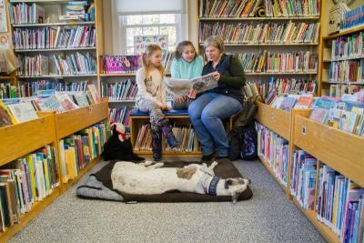 Amos sleeps while owner Holly Langenfeld reads with Paige Devine and Maisie Lacklan. Photo by: Andrew W. Griffith