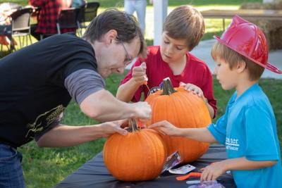 Chuck Kanaly, left, helps his sons William, middle, and Henry carve pumpkins during the Pumpkin Palooza on Oct. 29. Photo by: Sawyer Smook-Pollitt