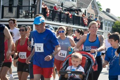 Runners, including 82-year-old Maurice “Mo” Bourque wearing number 74, take off down Water Street at the start of the race. Photo by Sawyer Smook-Pollitt