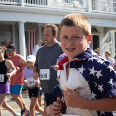 Needham resident Declan O’Brien, 14, wears a patriotic shirt while running the July 4 Road Race in Mattapoisett. Photo by Sawyer Smook-Pollitt