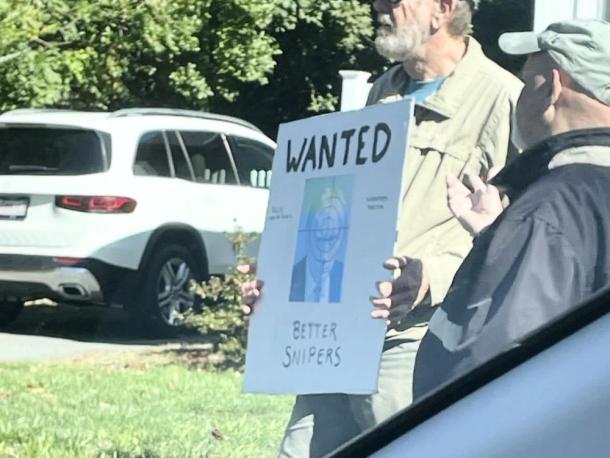 A protestor at the Mattapoisett "No Kings" rally holds a violent sign, leading to a police investigation.