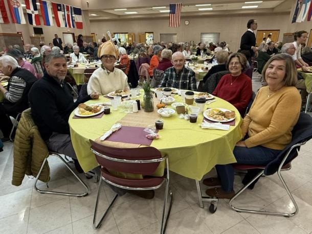 Friends and the community smile together at shared tables.