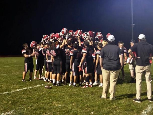 After the big win, the players raise their helmets in a huddle.