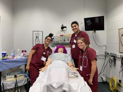 Shaw (front right) and two other students pose with a STAN patient simulator. Photo courtesy of Delaney Shaw.