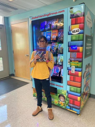 Julia Cabral picks up a copy of “I Survived” from the vending machine.