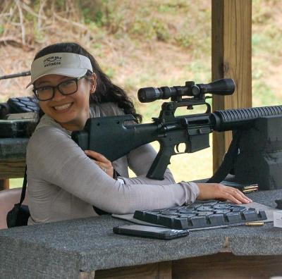 Participant smiles at the camera ready to shoot a rifle at the 100 yard range. Photos by Mari Huglin Participant smiles at the camera ready to shoot a rifle at the 100 yd range. Photos by Mari Huglin