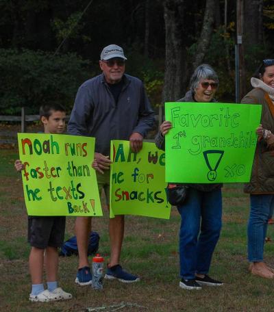 From left to right: Nixon Forcier, Mark Robert and Rose Robert cheer on Noah Robert-Howley with creative signs. From left to right: Nixon Forcier, Mark Robert and Rose Robert cheer on Noah Robert-Howley with creative signs.