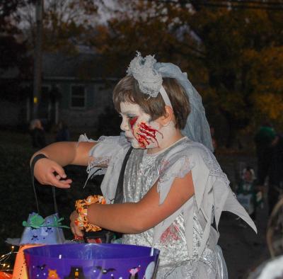 A trick-or-treater grabs some candy in their scary makeup.