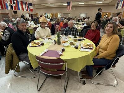 Friends and the community smile together at shared tables.