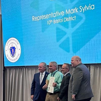 Rep. Mark Sylvia with Village Signs at Manufacturer of the Year Award Event. Source: Office of the State Rep. Mark Sylvia 