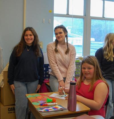 Bridget Coryer and Libby Achilles smile with a student.