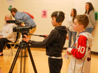 Some students practice broadcast journalism skills during the assembly.