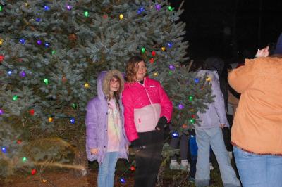 Kids pose in front of the lit tree.