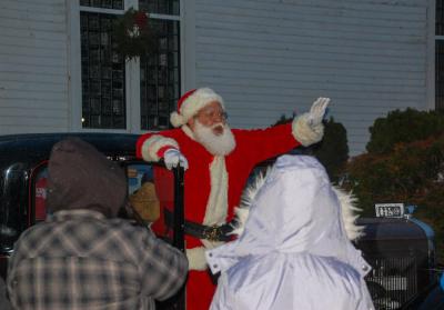 Santa arrives in a classic automobile to bring Christmas cheer.