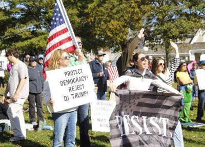 Emily Nugent of Mattapoisett holds a poster encouraging attendees to "Protect Democracy" while Avery Nugent holds a "Resist" flag at the Mattapoisett "No Kings" protest on Saturday, Oct. 18. Photo by Grace Ann Natanawan