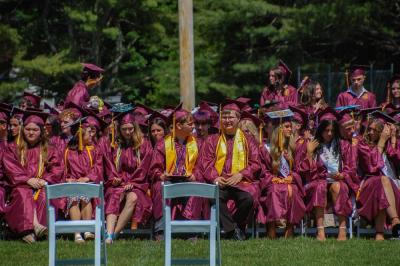Graduates sit on the Old Colony field. 