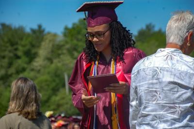 A student leaves the stage, diploma in hand. 