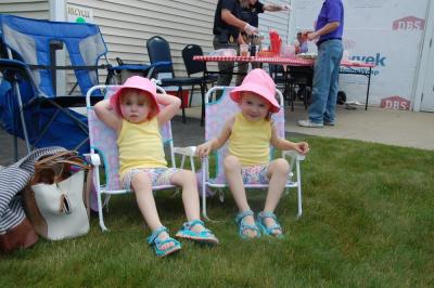 Three-year-old twins Rachel, left, and Hailey kick back at the car show. 