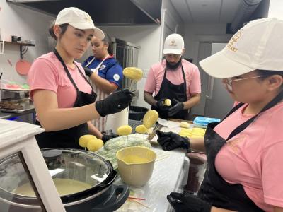 Bakery employees dip mango-flavored pastries in white chocolate. 