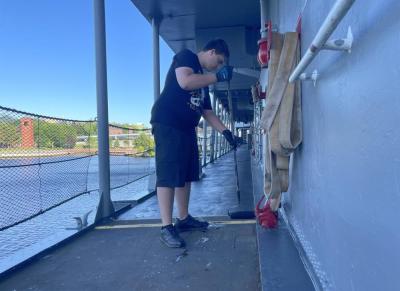 Bryan Correia paints the deck of a boat at Battleship Cove. 