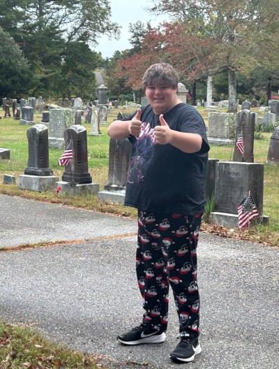 Cole Gretton poses in front of some of the graves he cleaned. 