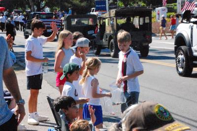 Kids pick up candy and wave at parade participants. 