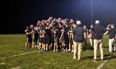 After the big win, the players raise their helmets in a huddle.