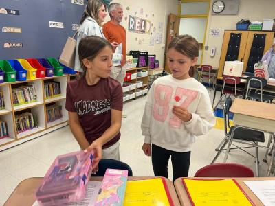 Reagan Tracy, left, and Mikey Waterman, both 8, chat and unpack school supplies. 