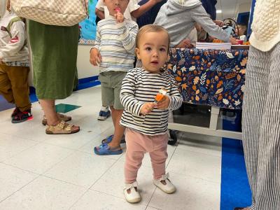 Holly, 1, plays with her lollypop while her mother directs new students and their parents to classrooms. 