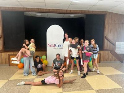 The group smiles near the community center's stage. 