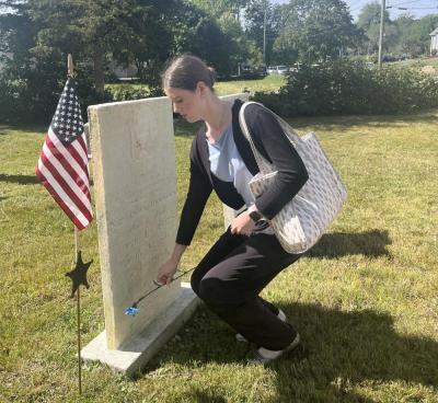 Madison Cable lays a carnation at the grave of a Revolutionary War soldier, honored at the ceremony after 250 years. Cable sang “The Star-Spangled Banner” and “God Bless America” for the ceremony.