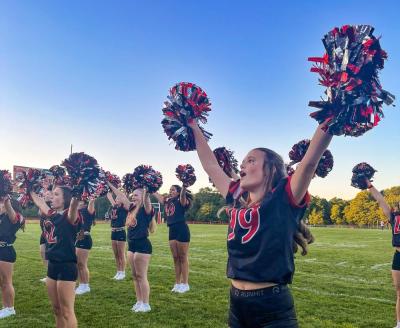 Libby Achilles cheers with pom poms held high.