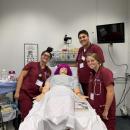Shaw (front right) and two other students pose with a STAN patient simulator. Photo courtesy of Delaney Shaw.