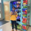 Julia Cabral picks up a copy of “I Survived” from the vending machine.