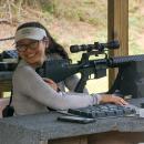 Participant smiles at the camera ready to shoot a rifle at the 100 yd range. Photos by Mari Huglin