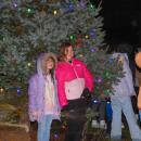 Kids pose in front of the lit tree.