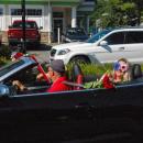 Courtney Nowick, right, smiles from a convertible decorated with flowers and flags.